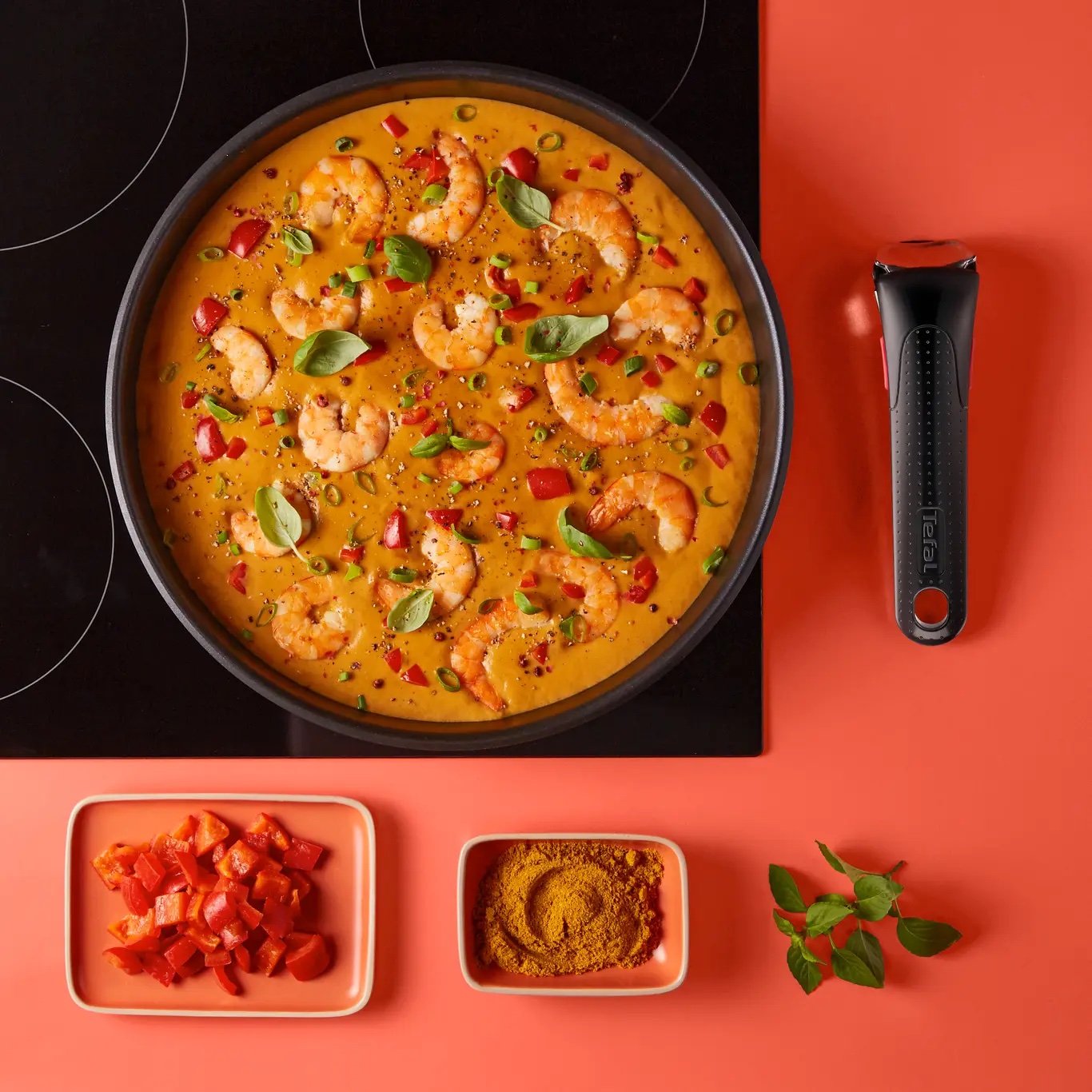 Sartén Ingenio con curry de langostinos sobre placa de inducción, con el mango extraíble al lado